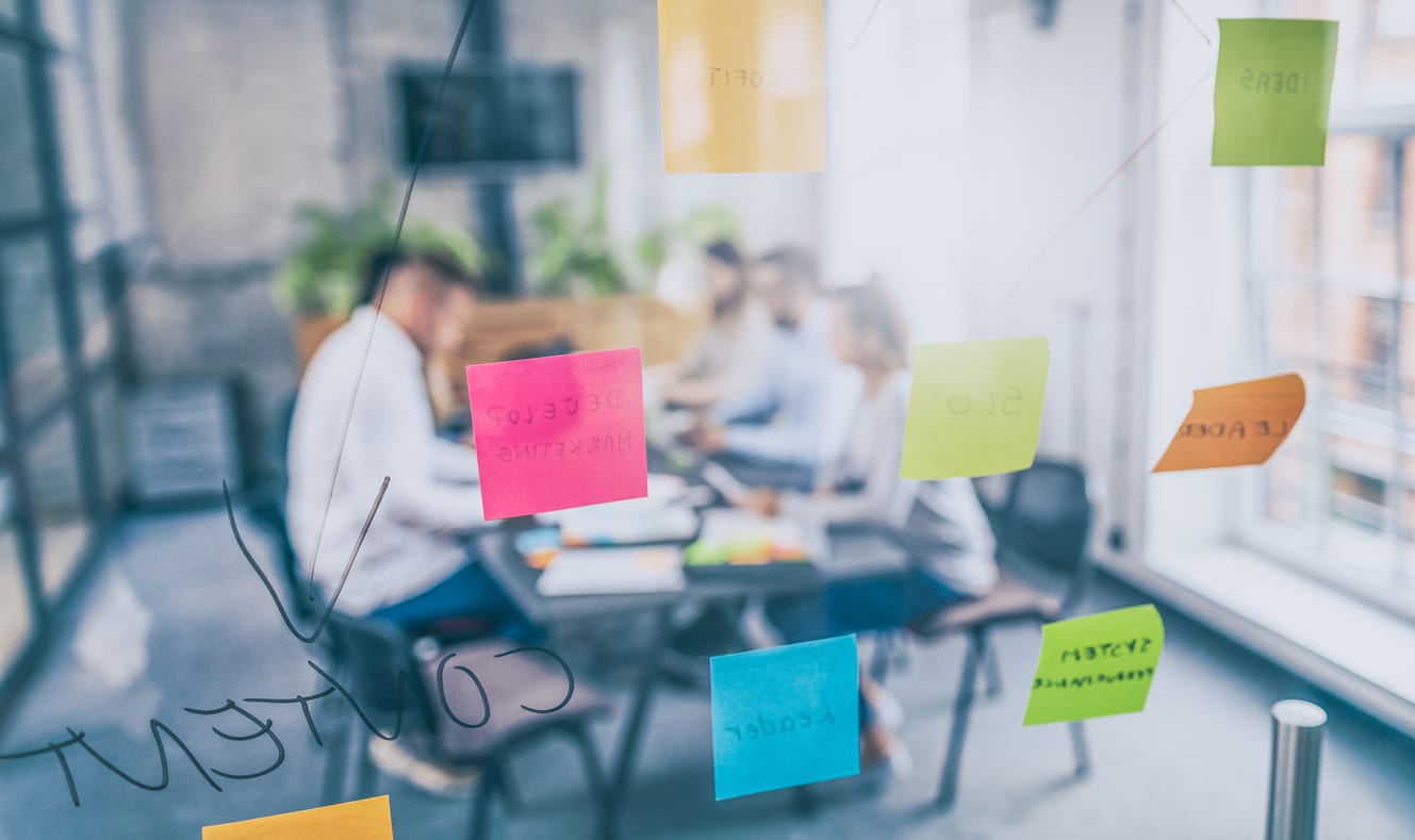 Business people meeting at office and use post it notes to share idea. Brainstorming concept. Sticky note on glass wall.