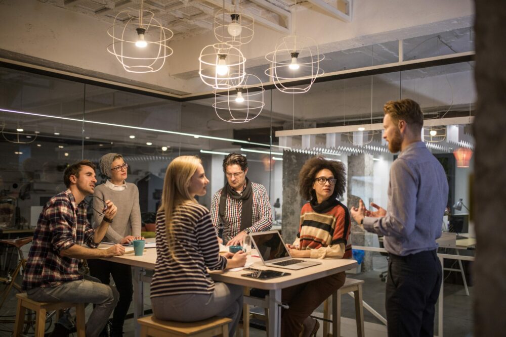 Redhead man talking to his team about new business ideas on a meeting in the office.